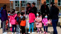 Children, some wearing face masks as a preventive measure, pick up free lunch at Kenmore Middle School in Arlington, Virginia on March 16, 2020, after schools in the area closed due to the coronavirus outbreak. - Stocks tumbled on March 16, 2020 despite emergency central bank measures to prop up the virus-battered global economy, as countries across Europe started the week in lockdown and major US cities shut bars and restaurants. The virus has upended society around the planet, with governments imposing restrictions rarely seen outside wartime, including the closing of borders, home quarantine orders and the scrapping of public events including major sporting fixtures. (Photo by ANDREW CABALLERO-REYNOLDS / AFP) (Photo by ANDREW CABALLERO-REYNOLDS/AFP via Getty Images)